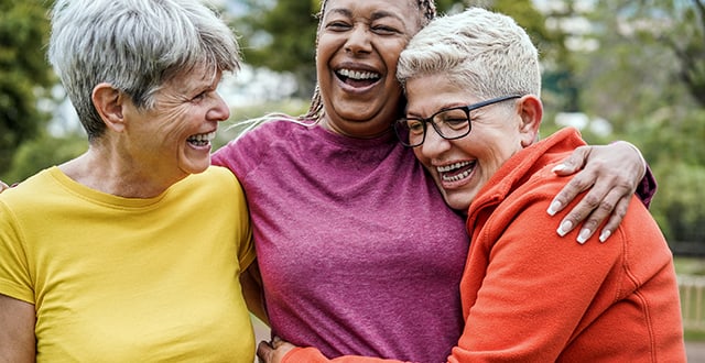 Three senior women hugging each other and laughing